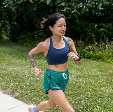 individual running along a path in a park in a sports bra