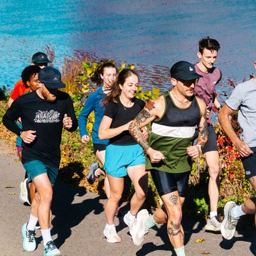 group of people jogging along a path by a body of water